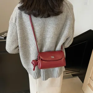 Sac bandoulière rétro en cuir rouge avec logo blanc et breloque animal mignonne