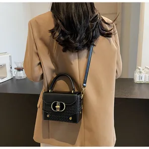 Detail of black leather handbag featuring woven texture and gold oval metal buckle clasp