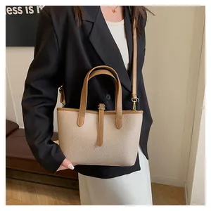 Close-up of beige lychee texture tote bag with brown handles and gold hardware details