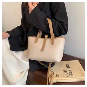 Chic cream litchi grain tote bag with brown handles styled on a leather seat