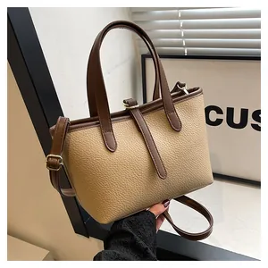 Detail of soft lychee pattern tote bag with dual brown handles and gold hardware