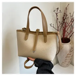 Close-up of cream pebble leather tote with brown straps and gold hardware detail