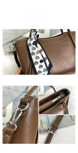 Detail of dark brown bucket bag with white stitching and heart pattern silk scarf handle