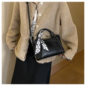 Detail of black textured bucket bag featuring heart pattern scarf on handle and silver buckles