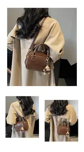 Detail of vintage brown crossbody bag with plush charm and embossed letter pattern