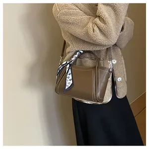 Close-up of brown leather bucket bag with contrast stitching and heart silk scarf