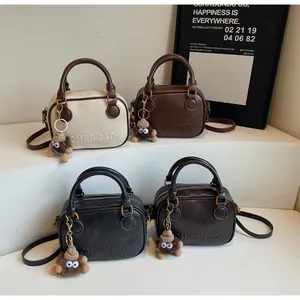 Close-up of four leather mini boston bags in various colors with fuzzy monster charms