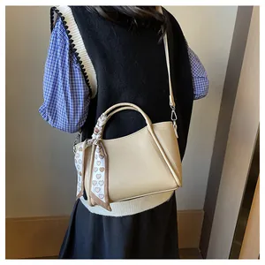 Beige bucket bag detail with textured finish and red heart pattern silk scarf accessory