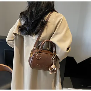 Detail of vintage brown leather handbag with luxury gold hardware and plush charm pendant