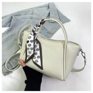 Detail view of cream bucket bag with black and white heart pattern silk scarf tied on handle