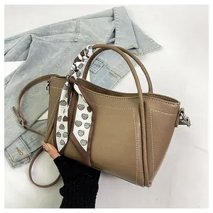 Detail of khaki PU leather bucket bag with white stitching and heart pattern scarf
