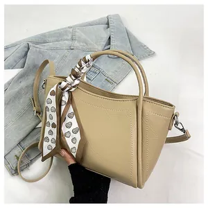 Detail of leaf pattern embossed bucket bag with decorative heart print silk scarf on handle
