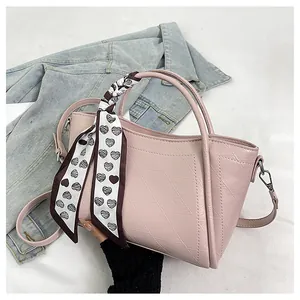 Detail of pink bucket bag with heart-print scarf handle on denim background