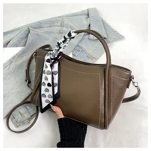 Detail of brown leather bucket bag featuring a decorative heart pattern silk scarf handle