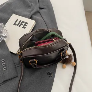 Retro brown crossbody bag with top handle and plush charm, shown with daily essentials