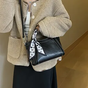 Chic black bucket bag with white contrast stitching and heart print silk scarf detail