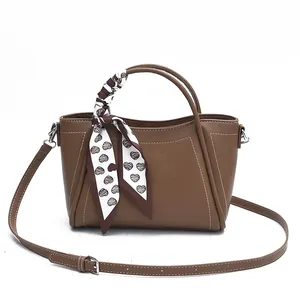 Chic brown bucket bag with croc texture and decorative heart-printed scarf on white background