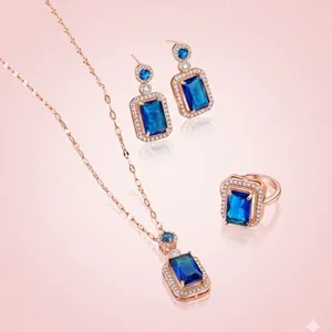 Parure élégante en or rose avec pierres bleu royal taille émeraude et halo de cristaux