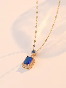 Détail du pendentif en zircon bleu saphir avec chaîne dorée et accents de diamants halo