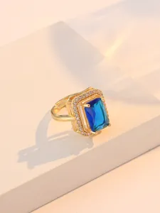 Détail de la bague dorée ajustable avec pierre bleue rectangulaire et zircons