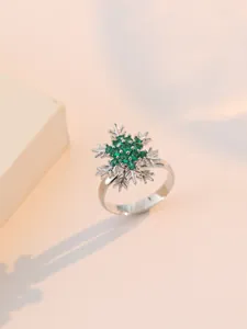 Dettaglio anello fiocco di neve in argento con zircone verde su sfondo rosa tenue