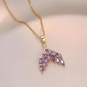 Elegant gold necklace featuring a fishtail pendant with purple marquise-cut stones