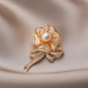 Elegante broche de camelia con pétalos de nácar, perla y lazo dorado con circones