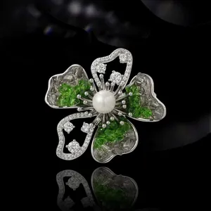 Elegant floral brooch with white pearl and crystal petals on black reflective surface