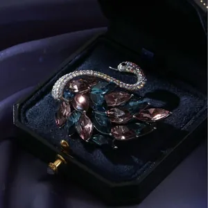 Broche cygne élégante avec pierres roses et bleues dans un écrin à bijoux de luxe
