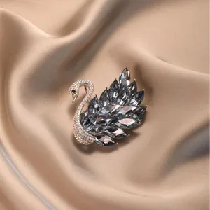 Broche cygne élégante avec cristaux colorés sur fond de soie de couleur champagne