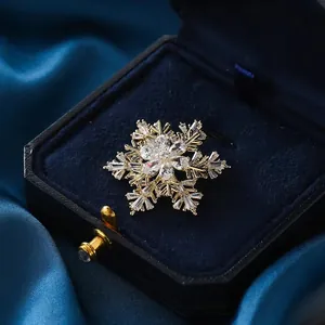 Broche de copo de nieve dorado con circonitas sobre un joyero de terciopelo azul