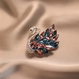 Élégante broche cygne avec cristaux de zircon colorés sur fond de satin champagne