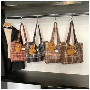 Detail of four plaid tote bags in various colors with cute bear pendants and side labels