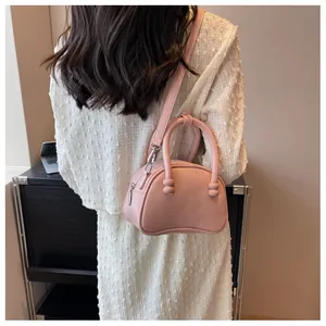 Rear view of model wearing pink PU crossbody bag with unique ball-shaped handle detail