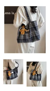 Detail of blue plaid tote bag with wide shoulder strap and pearl bear charm decoration