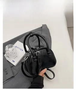 Close-up of a black textured faux leather handbag placed on a grey suit fabric