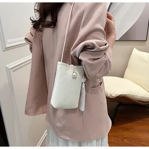 Détail du sac bandoulière crème élégant avec une grande perle et un long gland décoratif