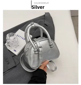 Detailed view of silver metallic croissant bag on grey blazer with matching shoulder strap