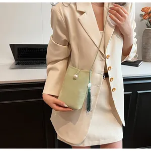 Gros plan du sac de téléphone vert clair en daim avec fermoir perle et détail de gland