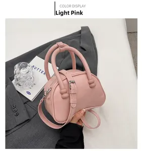 Close-up of light pink square crossbody bag with round handles and fine leather texture