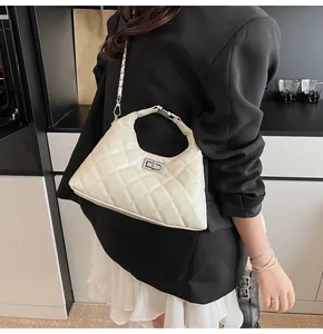 Sac à bandoulière matelassé blanc cassé avec chaîne porté sur blazer noir et jupe blanche
