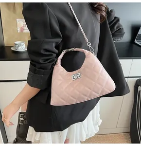 Détail du sac hobo rose matelassé avec fermoir rotatif et bandoulière chaîne sur modèle