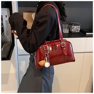 Detail of dark red glossy leather shoulder bag with creative baseball glove charm