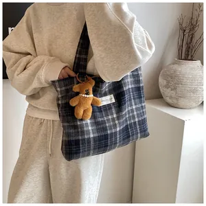 Detail of vintage plaid tote bag with plush bear charm and sturdy canvas straps