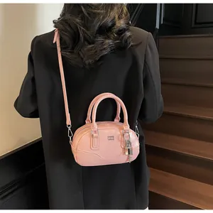 Sac Boston rose porté par un mannequin montrant la bandoulière réglable et la taille mini