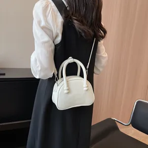 White mini semi-circular leather handbag with shoulder strap worn by model