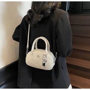 Détails du sac Boston en cuir blanc cassé avec ferrures dorées et cadenas décoratif