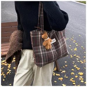 Detail of vintage plaid tote bag featuring a cute plush bear charm with pearl necklace