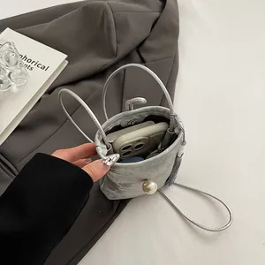 Mini sac seau perlé argenté avec fermoir perle et fine bandoulière au style épuré