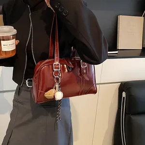 Retro burgundy rectangular handbag with polished finish and baseball charm on a model